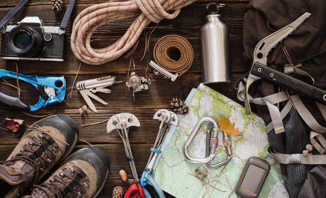 Equipment necessary for mountaineering and hiking on wooden background